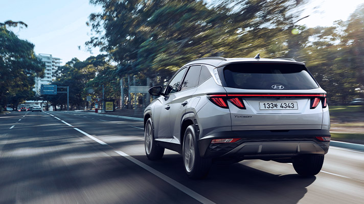 Hyundai TUCSON Hybrid driving down the road rear view